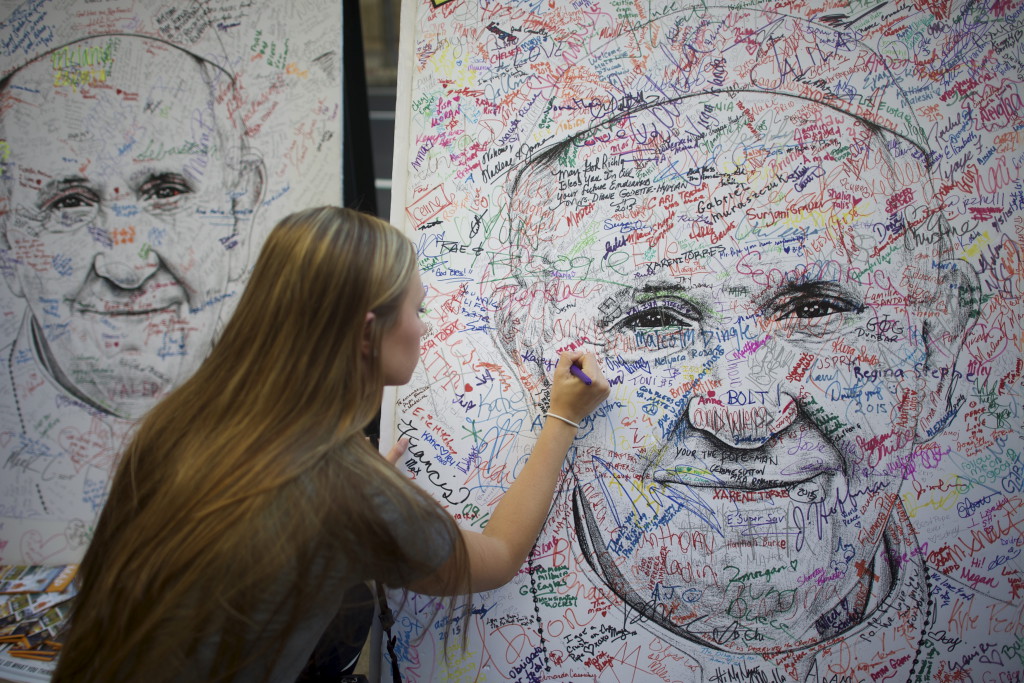 Franziskus als Projektionsfläche: Eine Studentin aus Minnesota unterschreibt auf einem Papstposter für Reformwünsche. (Foto: Reuters/Mark Makela) 